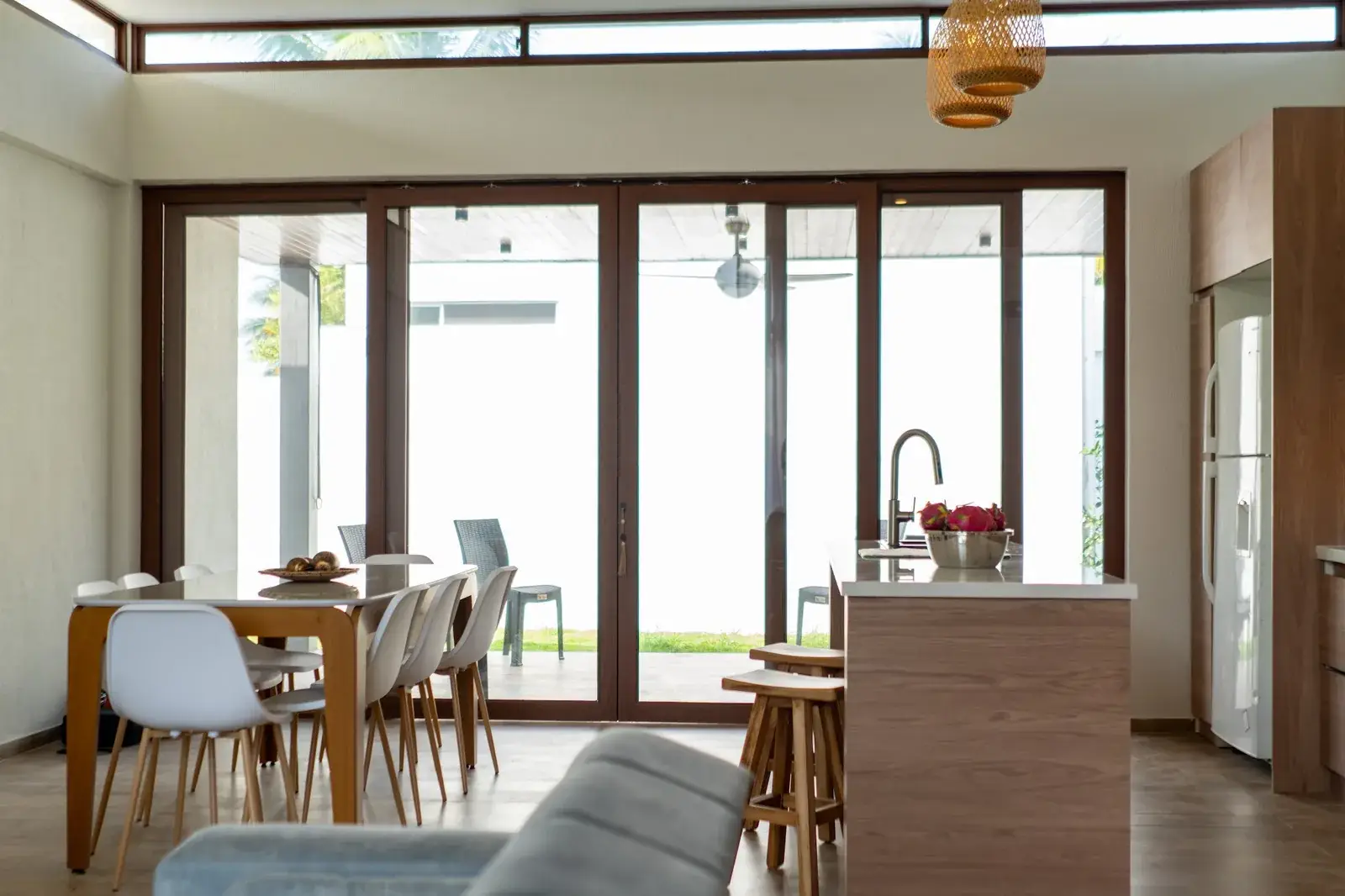 Sala y comedor de una propiedad Airbnb fotografiados con luz natural, con cocina de isla y puertas de vidrio hacia el patio