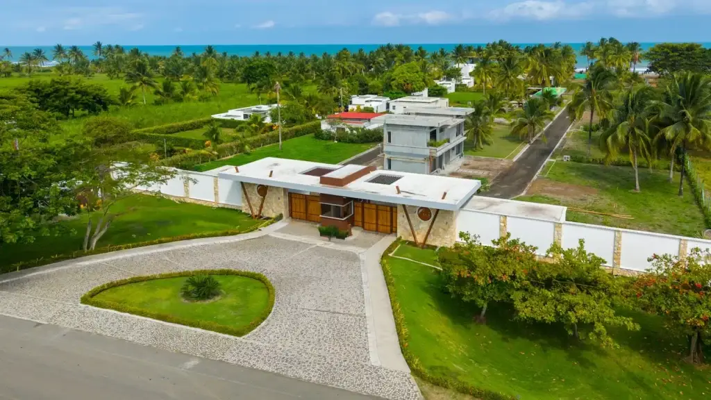Fotografía aérea con drone de la entrada de un condominio residencial costero rodeado de palmeras